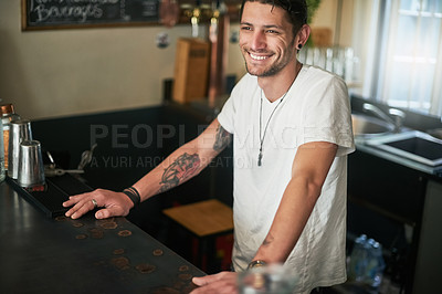 Buy stock photo Shot of a happy young bartender standing behind the counter in a bar
