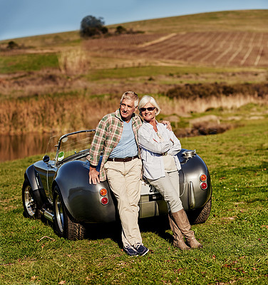 Buy stock photo Shot of a happy senior couple posing next to a convertible while out on a roadtrip