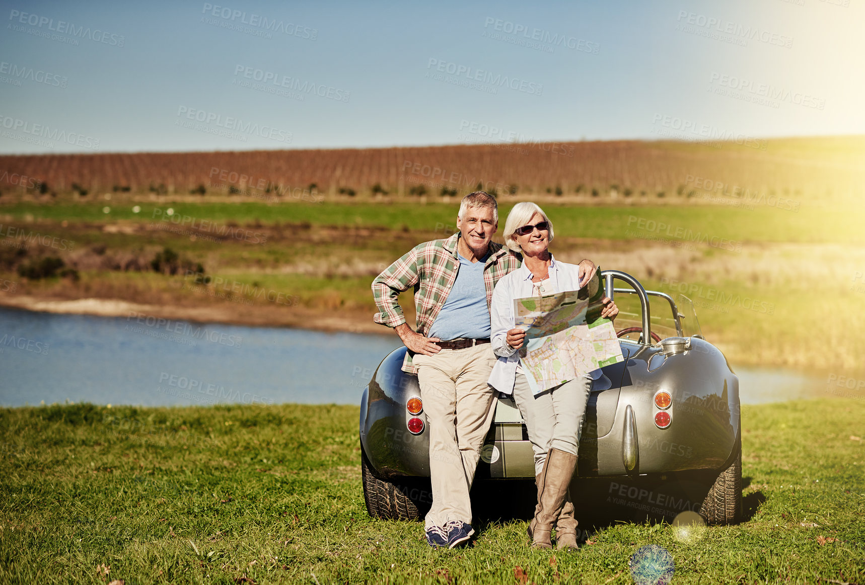 Buy stock photo Shot of a happy senior couple posing next to a convertible while out on a roadtrip