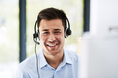 Buy stock photo Portrait of a happy young man wearing a headset and using a computer at work