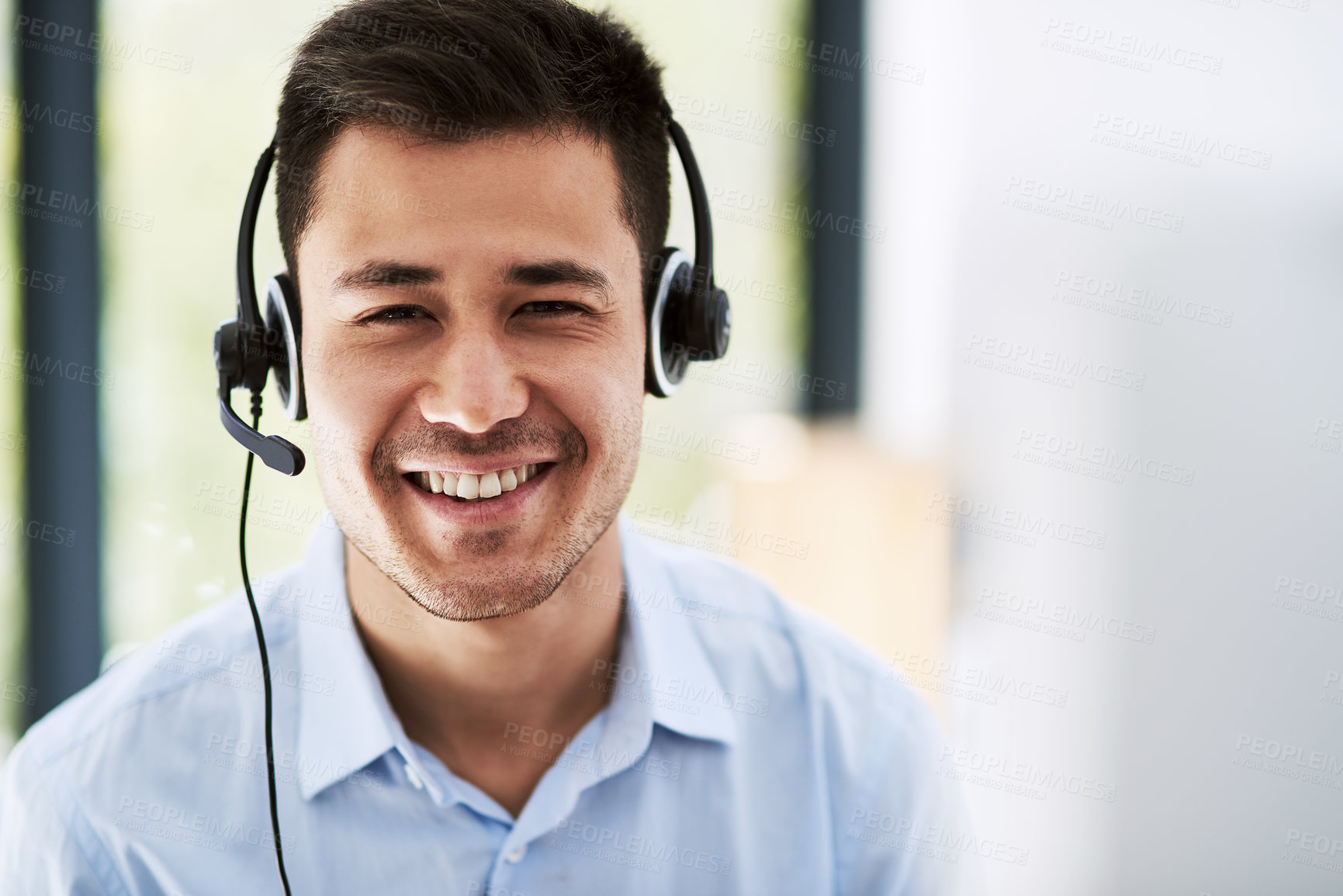 Buy stock photo Portrait of a happy young man wearing a headset and using a computer at work