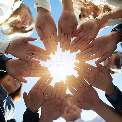 Buy stock photo Low angle shot of a group of businesspeople joining their hands together in unity