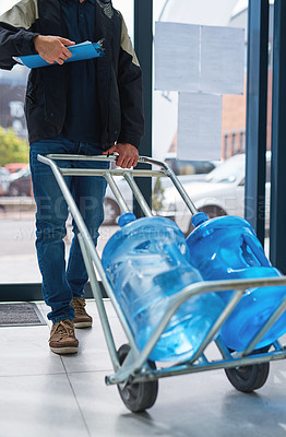 Buy stock photo Cropped shot of a courier making a bottled water delivery in an office