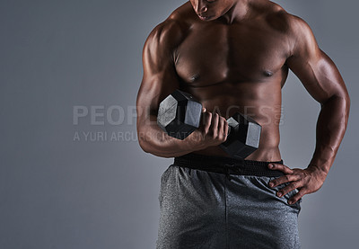 Buy stock photo Cropped shot of an athletic young man working up with a dumbbell