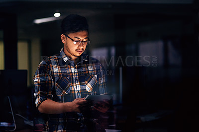 Buy stock photo Shot of a male designer working on a digital tablet late in the office