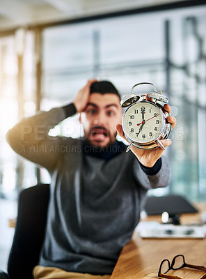 Buy stock photo Portrait of a young designer holding an alarm clock and looking stressed out while working in an office