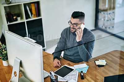 Buy stock photo Shot of a young designer talking on a cellphone while working in an office