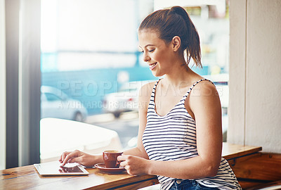 Buy stock photo Shot of a young woman using her digital tablet in a coffee shop