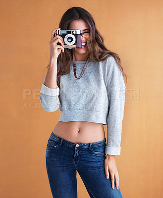 Buy stock photo Studio shot of a young woman holding her camera against a colorful background