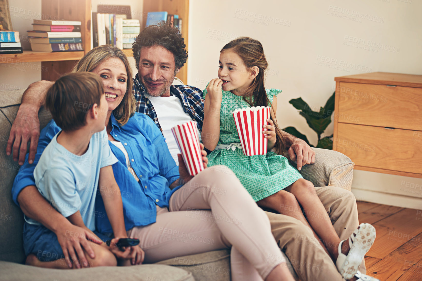 Buy stock photo Happy family, relax and watching tv with popcorn for movie, weekend or holiday on living room sofa at home. Mom, dad and children with smile and enjoying show, series or streaming service at house