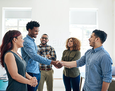 Buy stock photo Shot of happy colleagues shaking hands in a modern office