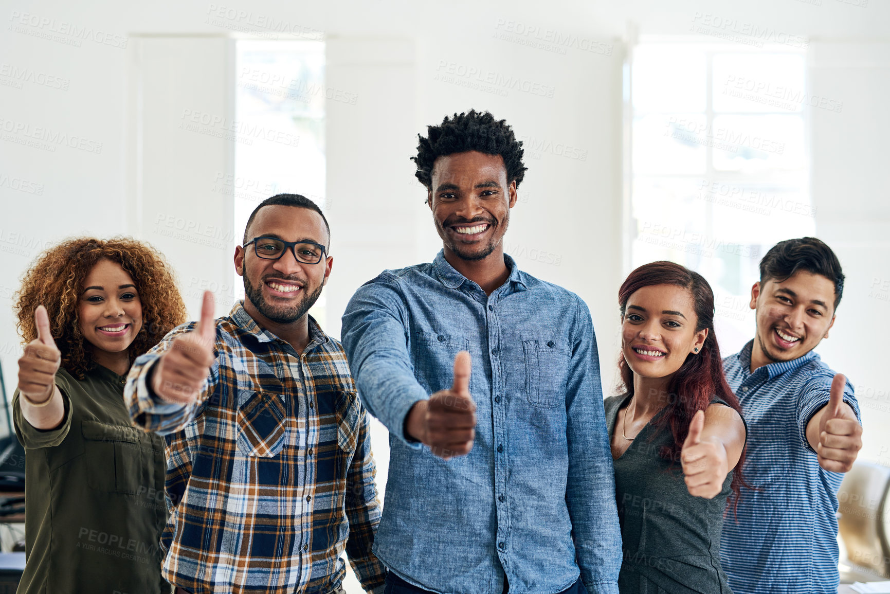 Buy stock photo Portrait of a team of happy colleagues showing thumbs up in a modern office