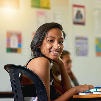 Buy stock photo Portrait of a happy young schoolgirl looking over her shoulder in class