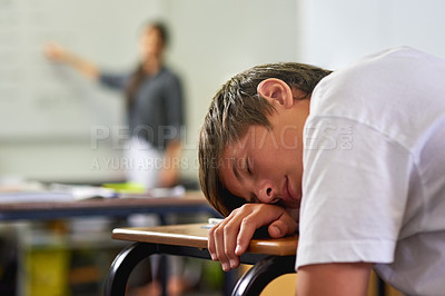 Buy stock photo Shot of a young schoolboy sleeping on his desk in class