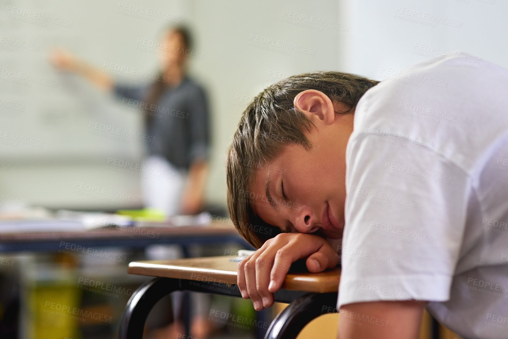 Buy stock photo Shot of a young schoolboy sleeping on his desk in class
