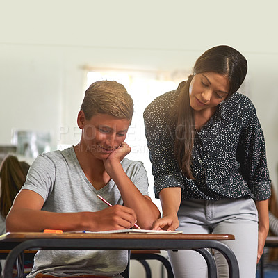Buy stock photo Shot of a young teacher explaining something to a student in her class