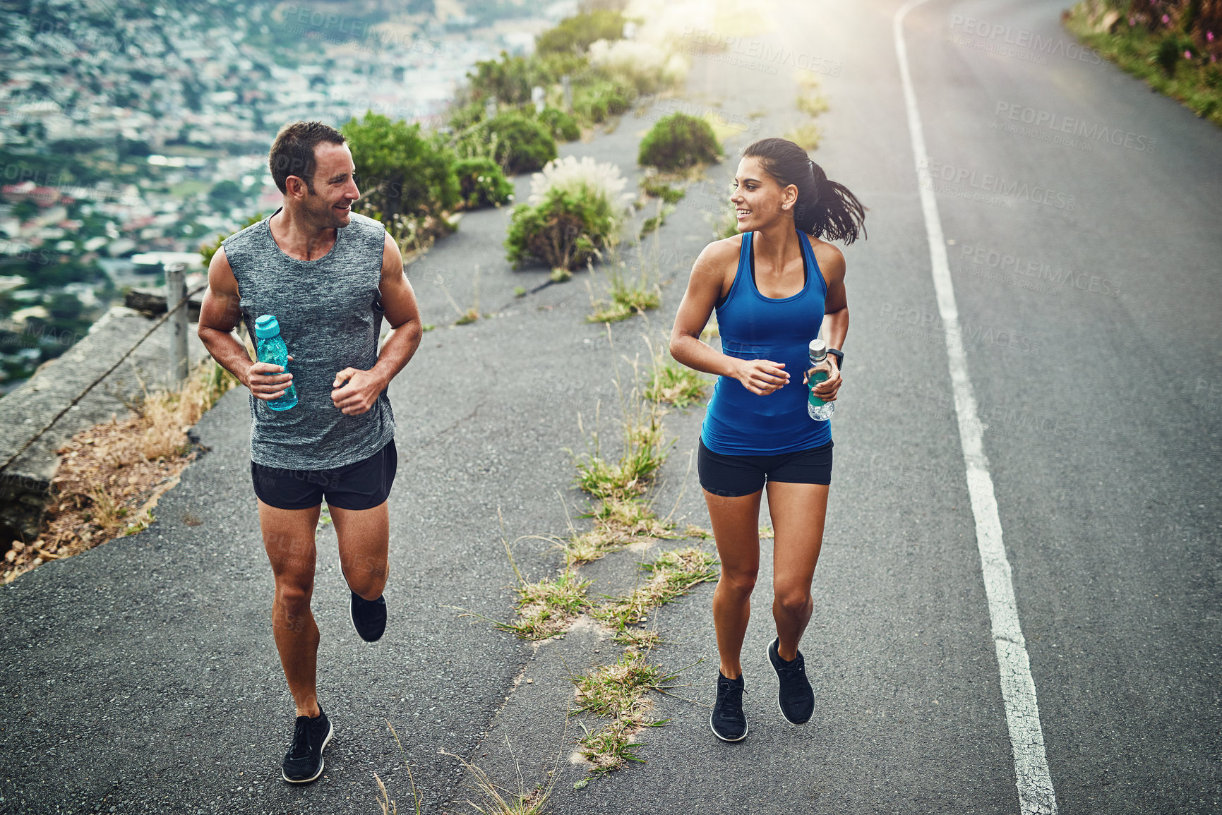 Buy stock photo Fitness, running and couple with smile, routine and bottle for hydration with water and outdoor. Road, exercise and people in morning, sportswear and training together, energy and workout for race