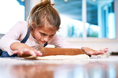 Buy stock photo Cropped shot of a little girl rolling out dough while baking at home