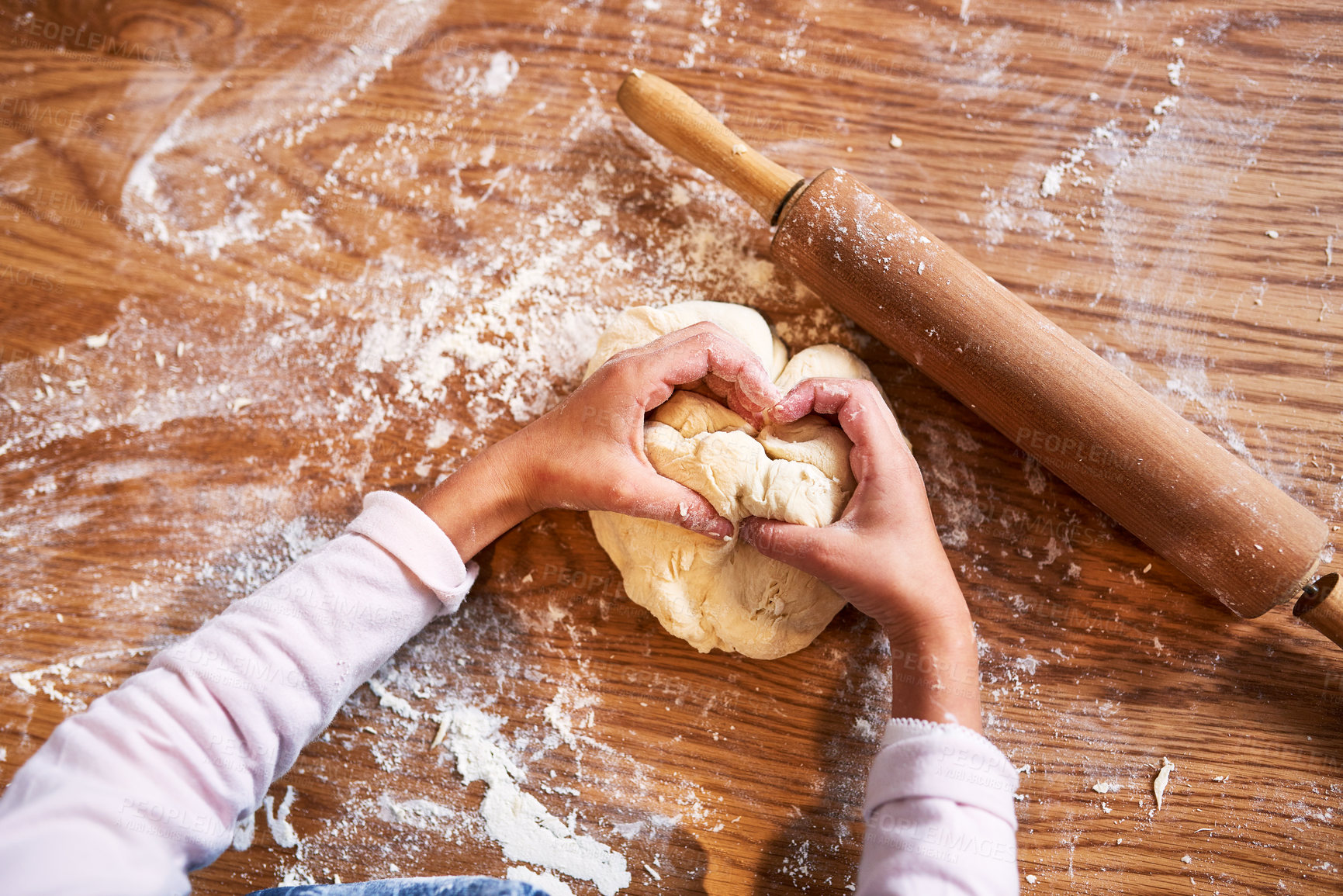 Buy stock photo High angle shot of a little girl kneading dough while baking at home