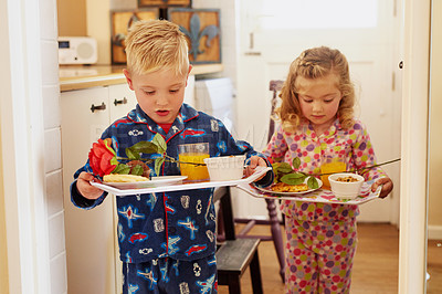 Buy stock photo Cropped shot of two little siblings carrying serving trays with breakfast at home