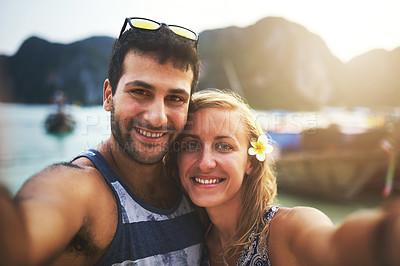 Buy stock photo Portrait of a young couple taking a selfie at the beach
