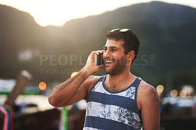 Buy stock photo Cropped shot of a young man talking on a cellphone at the beach