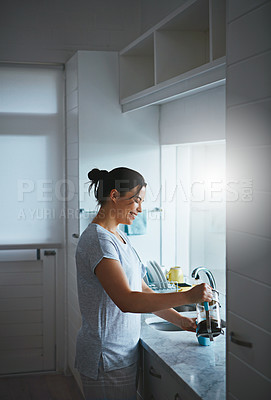 Buy stock photo Cropped shot of an attractive young woman preparing a pot of coffee in the kitchen