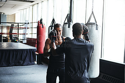 Buy stock photo Shot of a male boxer practising his moves with his coach