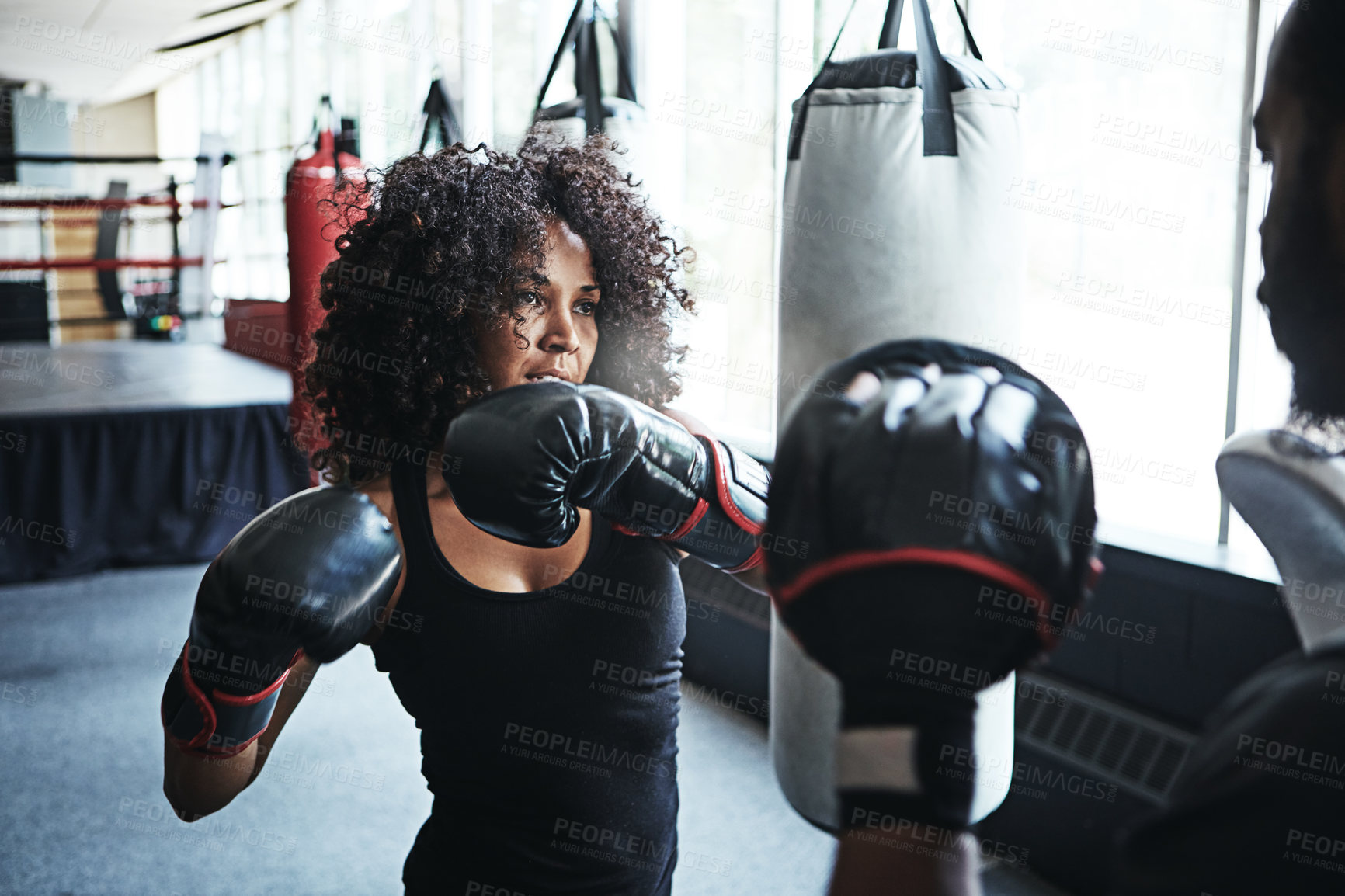 Buy stock photo Shot of a female boxer practising her moves with her coach