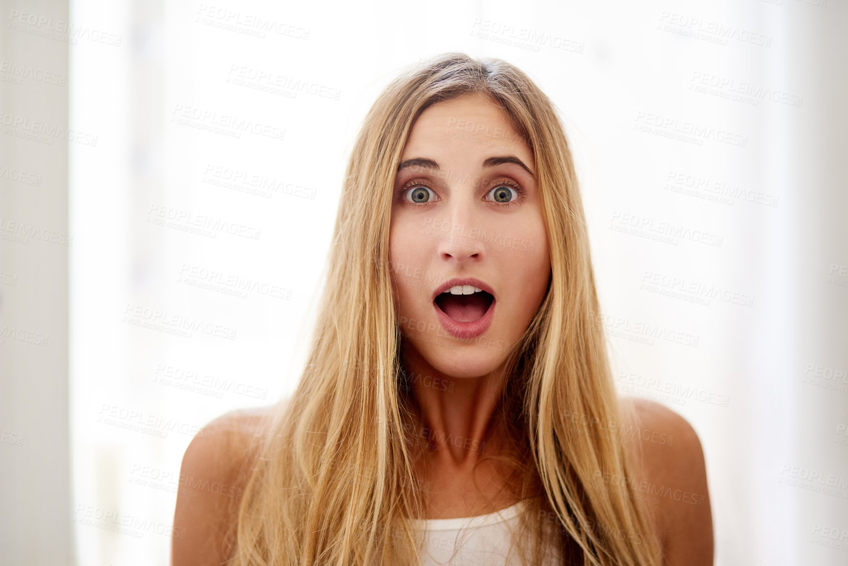 Buy stock photo Portrait of a young woman pulling a surprised face at home