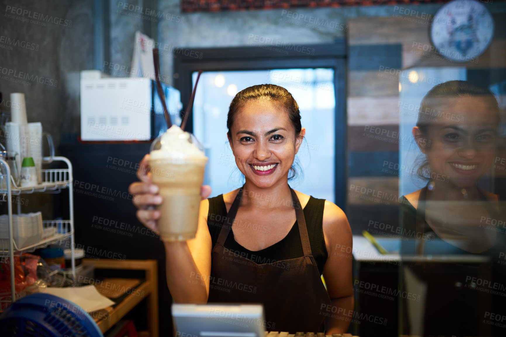 Buy stock photo Portrait of a young barista holding up a chilled coffee beverage in a coffee shop