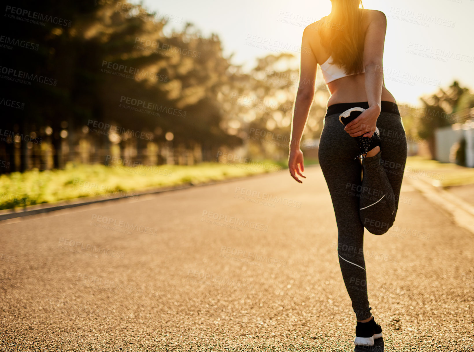 Buy stock photo Rearview shot of an unidentifiable young woman stretching before a run