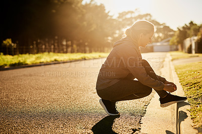 Buy stock photo Shot of a young woman tying her shoelace before going on a run
