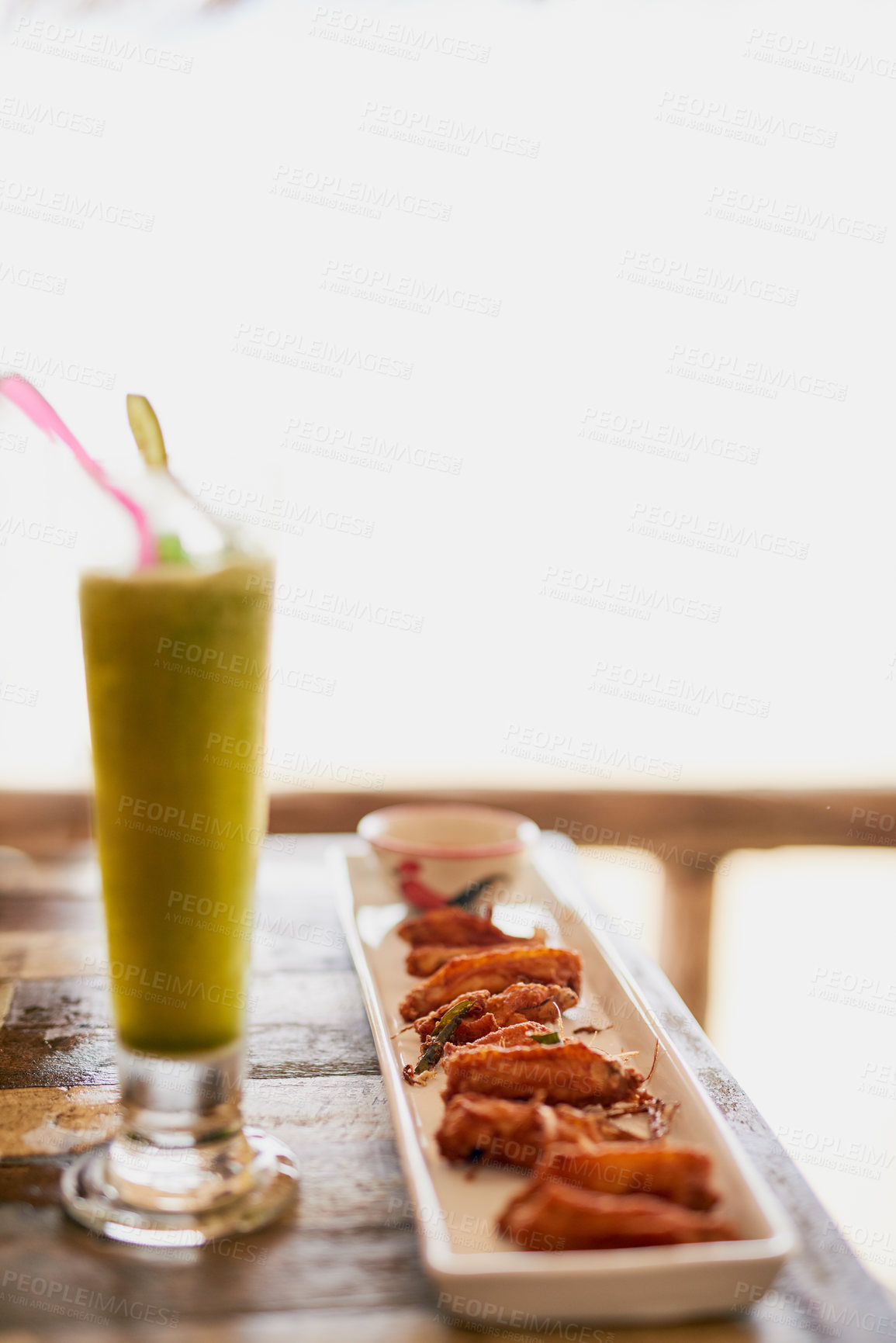 Buy stock photo Shot of chicken wings and a shake sitting on a table in an oceanside restaurant in Thailand