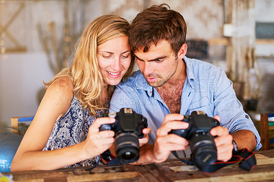 Buy stock photo Shot of a young couple looking at pictures on their camera while on holiday in Thailand