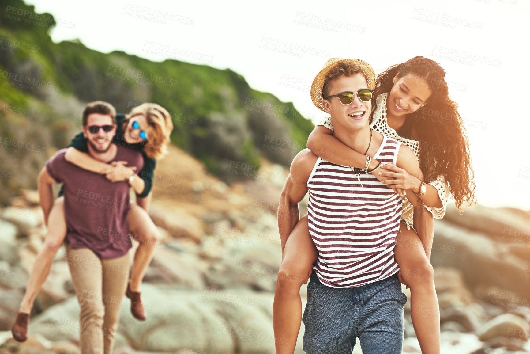Buy stock photo Cropped shot of two affectionate young couples enjoying their time on the beach