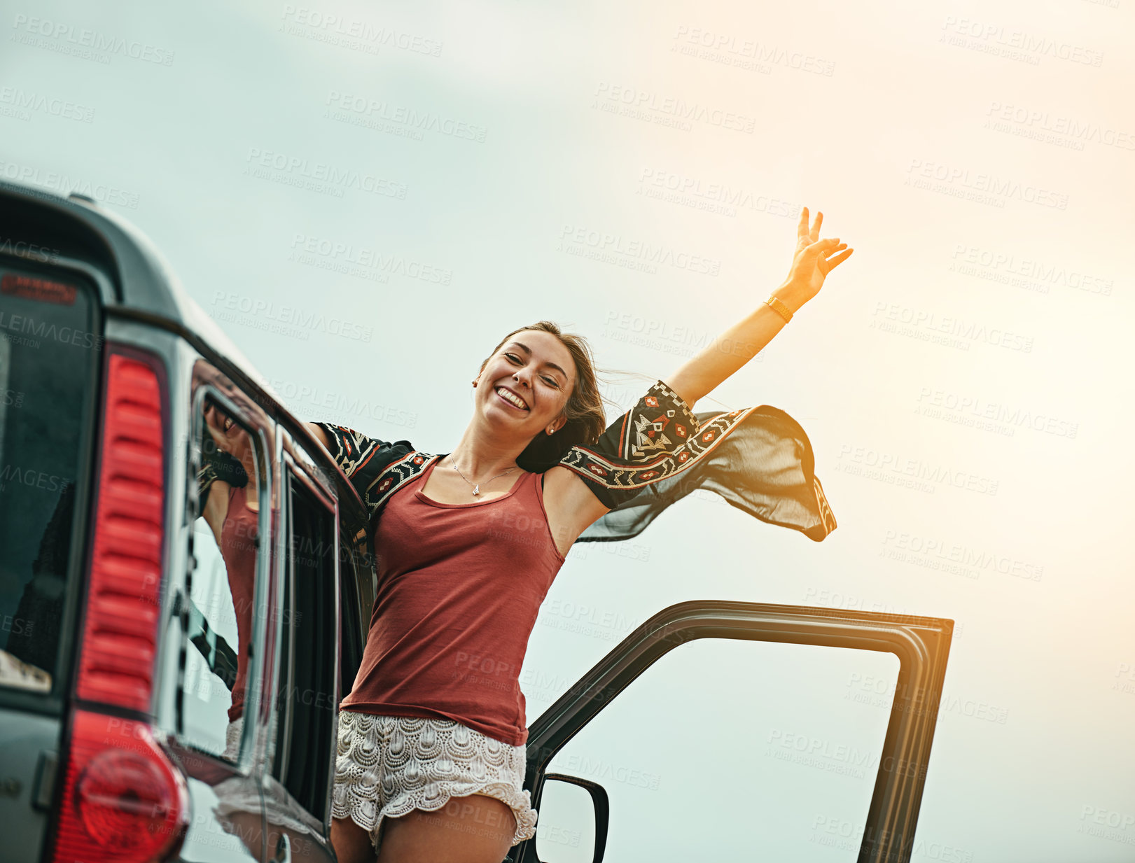 Buy stock photo Portrait of a young woman leaning out a car with her arms outstretched while on a roadtrip