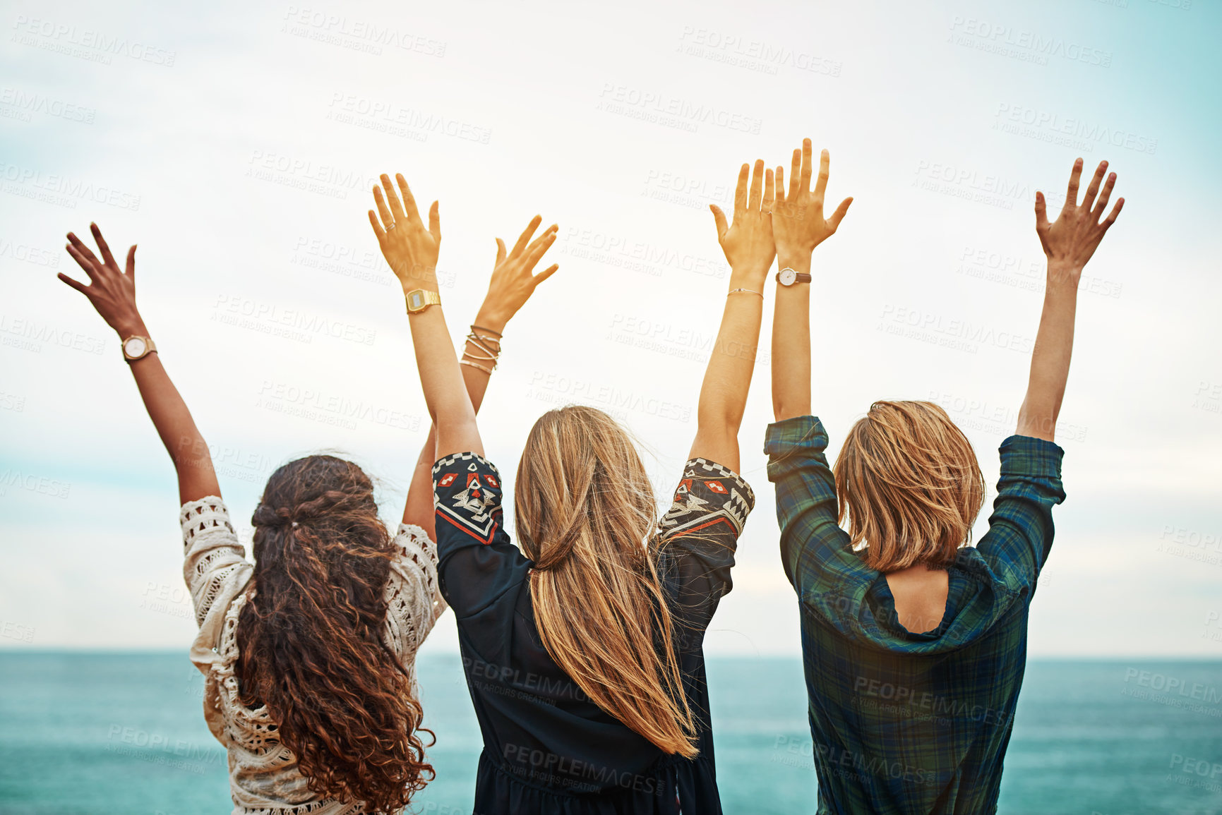Buy stock photo Rear view shot of a group of friends standing with their arms outstretched outside
