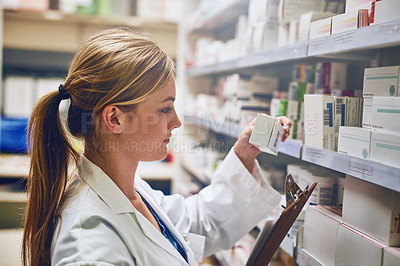 Buy stock photo Shot of a pharmacist looking at medication on a shelf