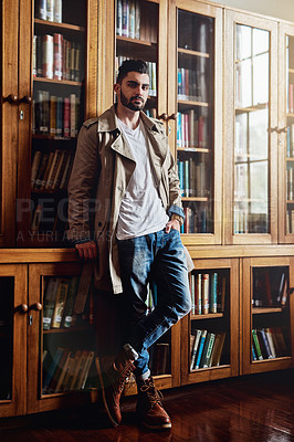 Buy stock photo Portrait of a handsome and stylish young man leaning against a bookcase at home