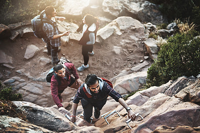 Buy stock photo Shot of a group of friends climbing a ladder while hiking in the mountains