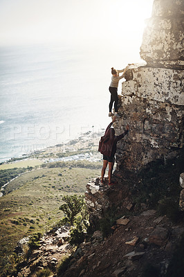 Buy stock photo Shot of a group of friends scaling the side of a mountain while out for a hike