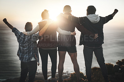 Buy stock photo Rearview shot of a group of friends standing with their arms raised on a mountain cliff