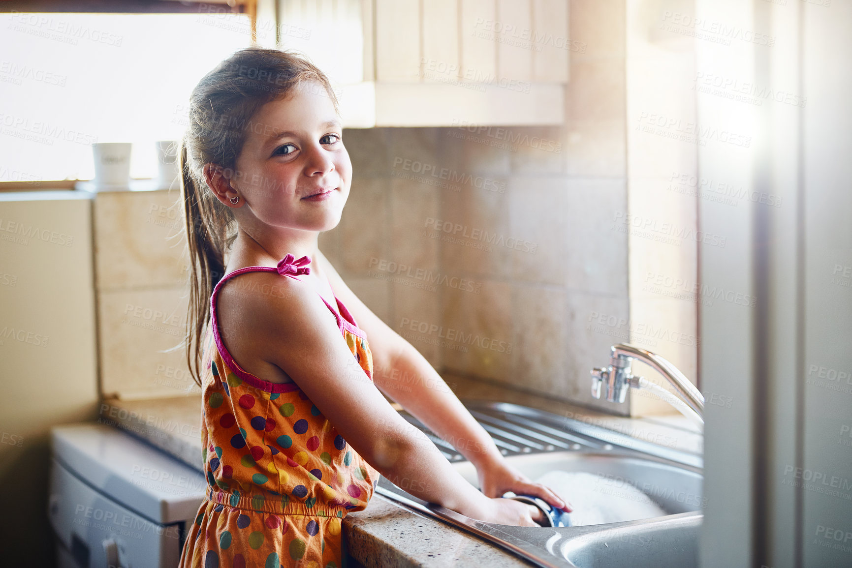 Buy stock photo Portrait of a little girl washing dishes at home
