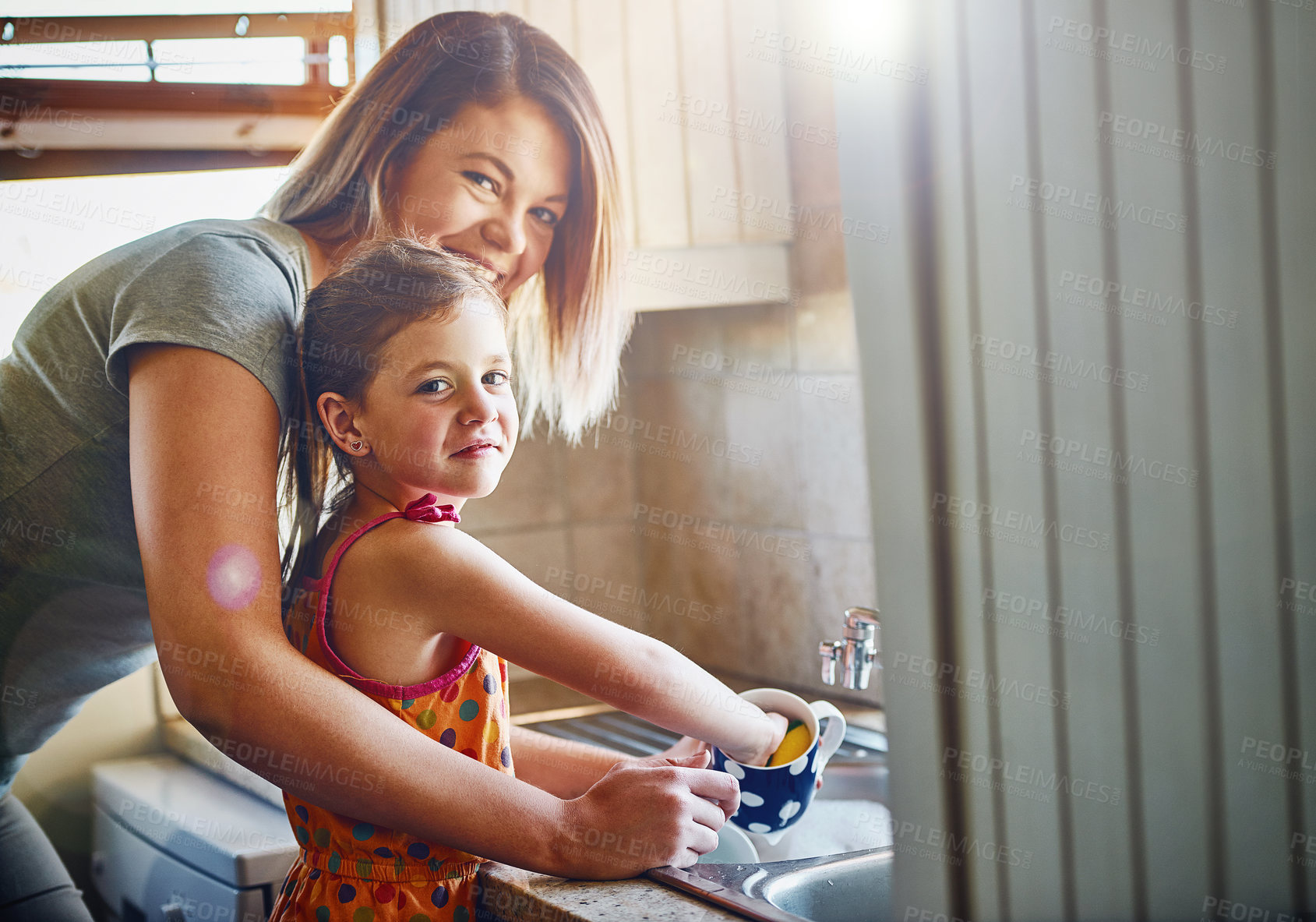 Buy stock photo Portrait of a mother and her little daughter washing dishes together at home