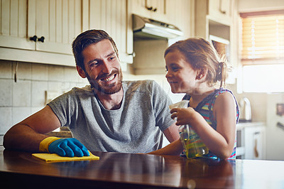 Buy stock photo Cropped shot of a father and his little daughter cleaning a kitchen surface together at home