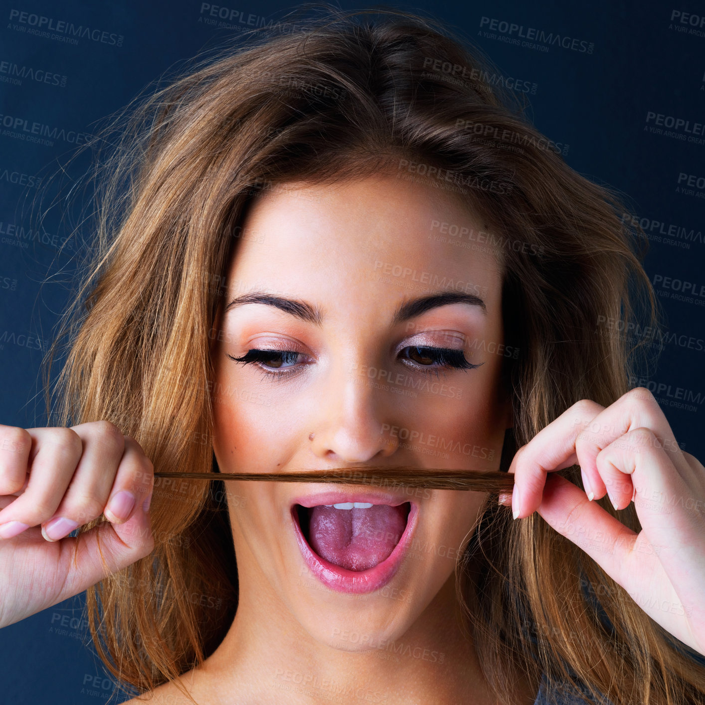 Buy stock photo Studio shot of a cute teenage girl making a mustache with her hair against a dark background