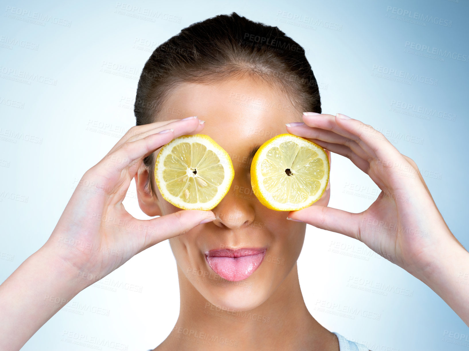 Buy stock photo Shot of a health-conscious young woman posing with lemons over her eyes in studio