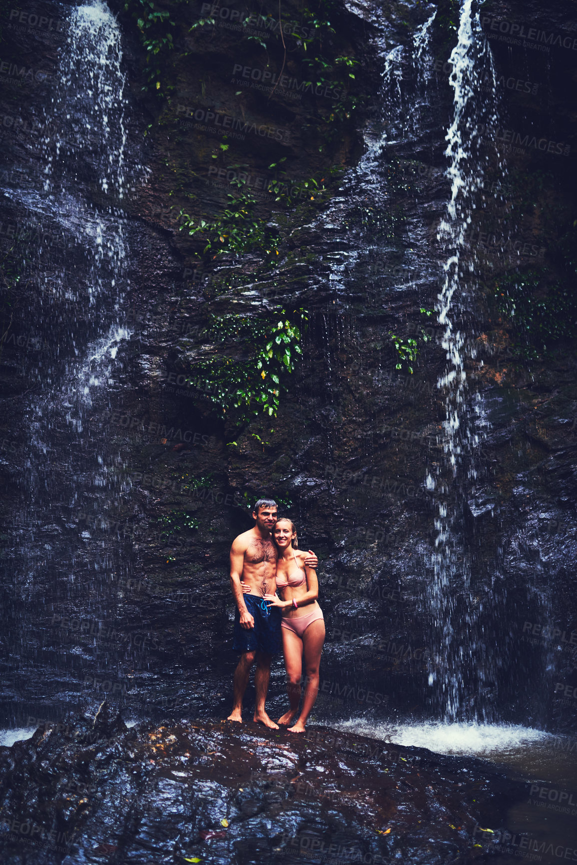 Buy stock photo Portrait of a happy young couple standing under a waterfall in the jungle