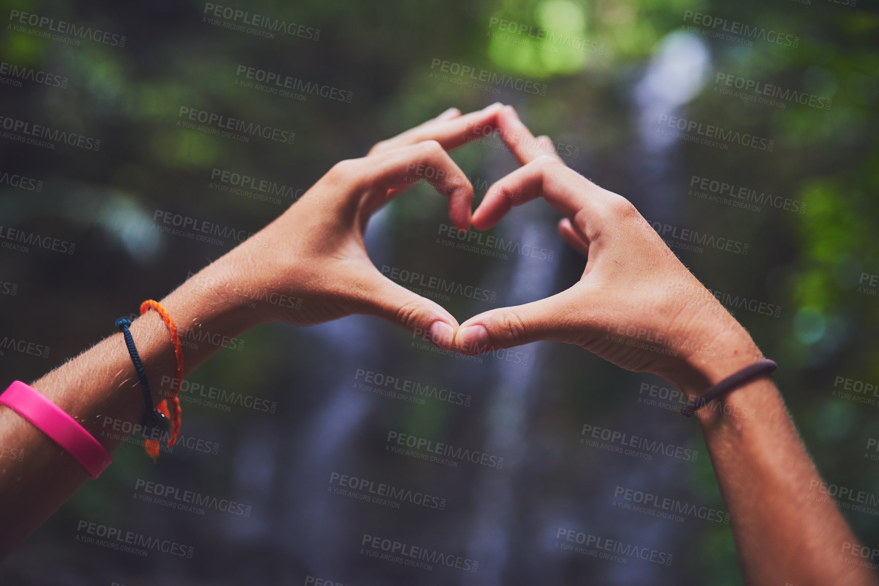 Buy stock photo Shot of an unidentifiable young woman making a heart gesture with her hands in the jungle